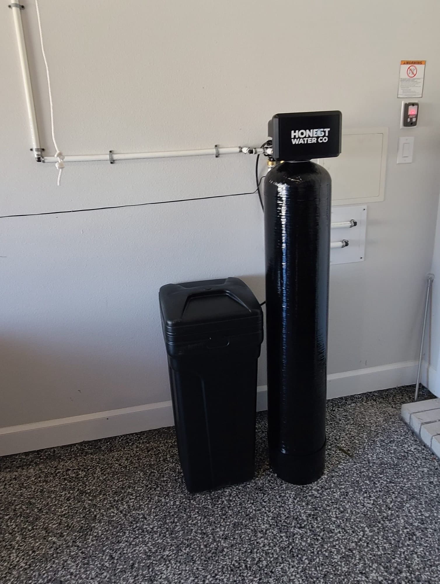Honest Water Co system installed in a carpeted garage with overhead pipe runs