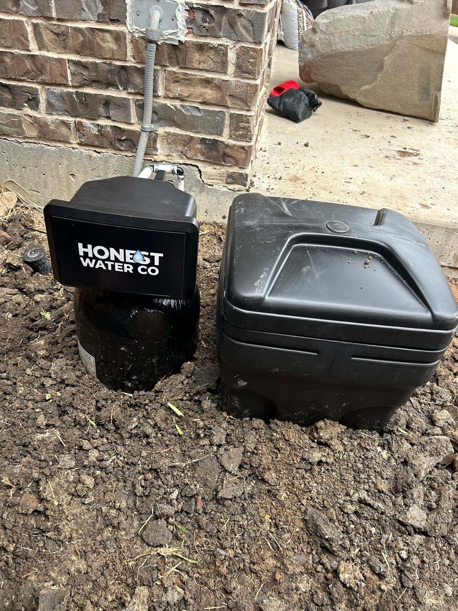 Honest Water Co tank and weatherproof brine tank cover installed outside a brick home