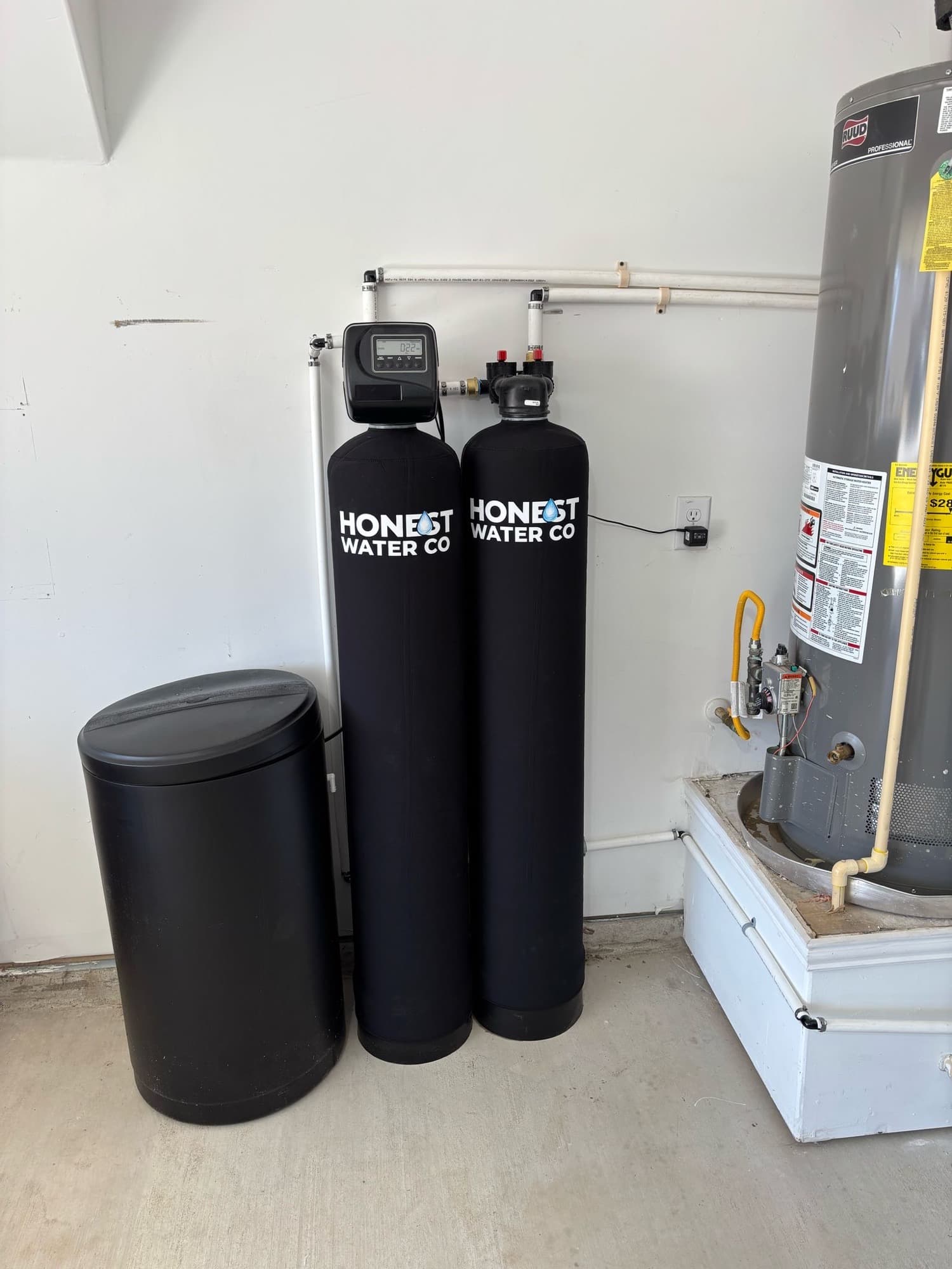 Two Honest Water Co tanks and a brine tank plumbed in beside the water heater