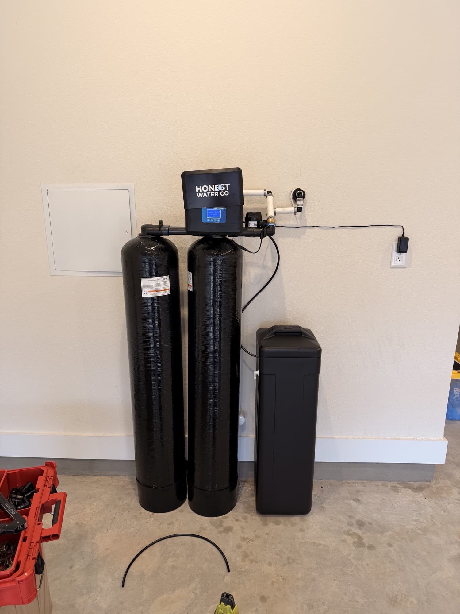 Twin Honest Water Co treatment tanks and brine tank installed against a garage wall