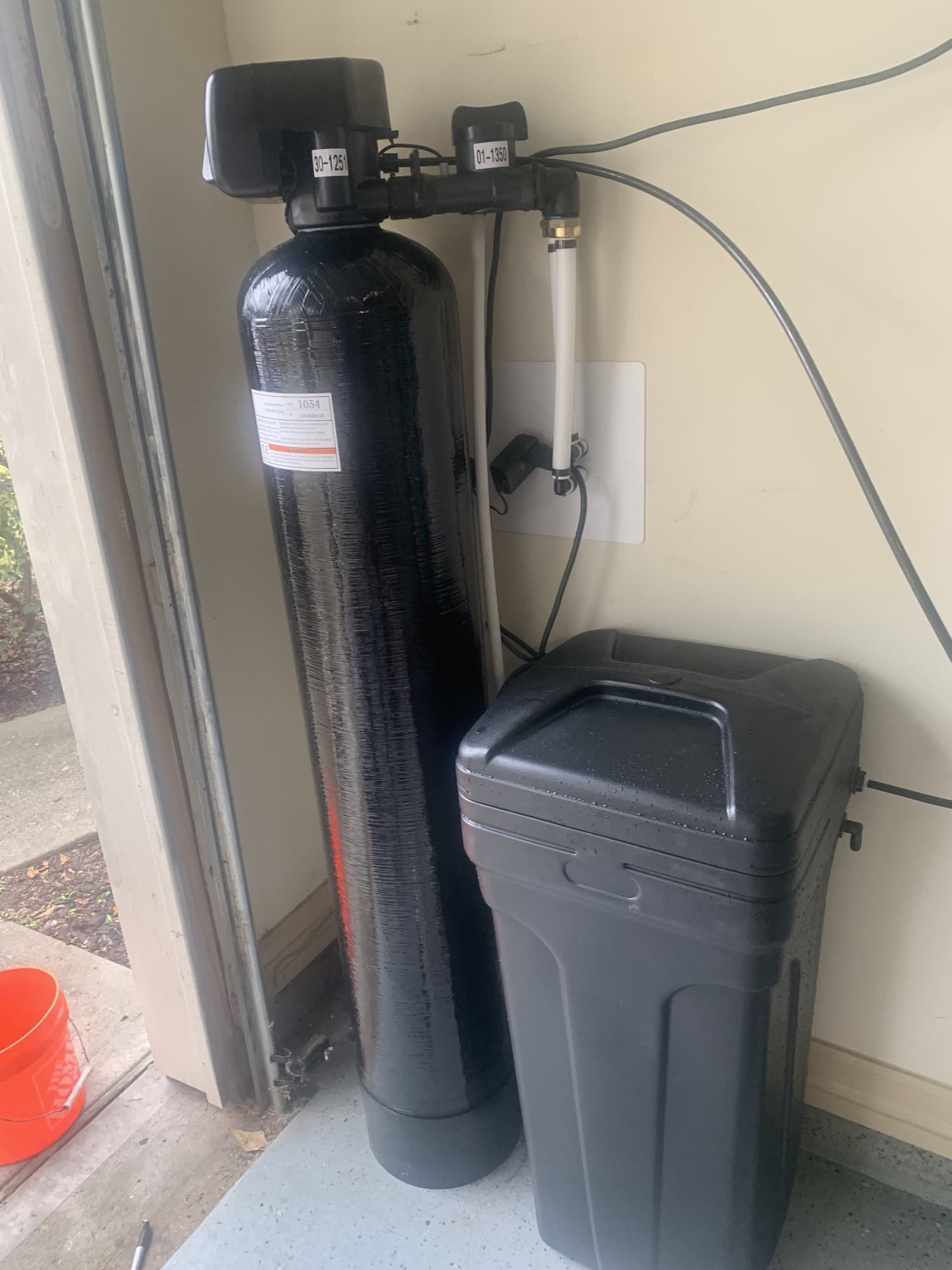 Water treatment tank and brine tank installed in a garage corner with neat pipework